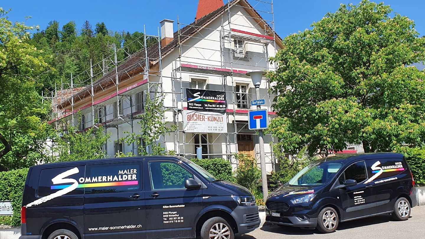 Zwei Firmenbusse von Maler Sommerhalder vor einem Haus mit Gerüst