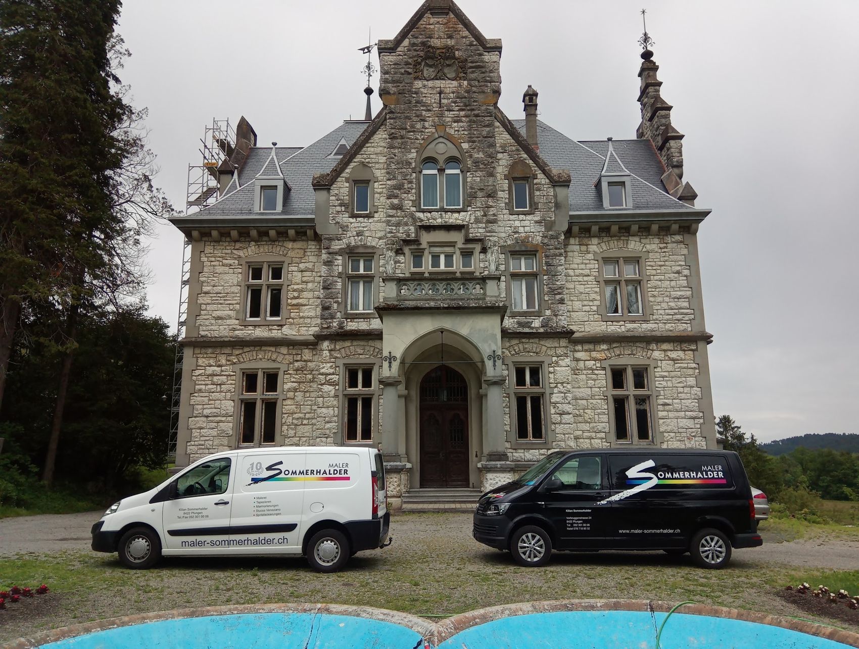 Firmenbusse vor einer Villa aus Naturstein